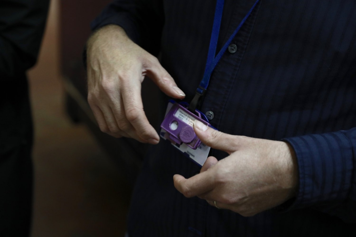 Close-up of a visitor’s lanyard card being slipped into a custom Arduino-powered “mission console” reader, which triggers the next branch of the installation’s narrative and records the team’s collective choice.