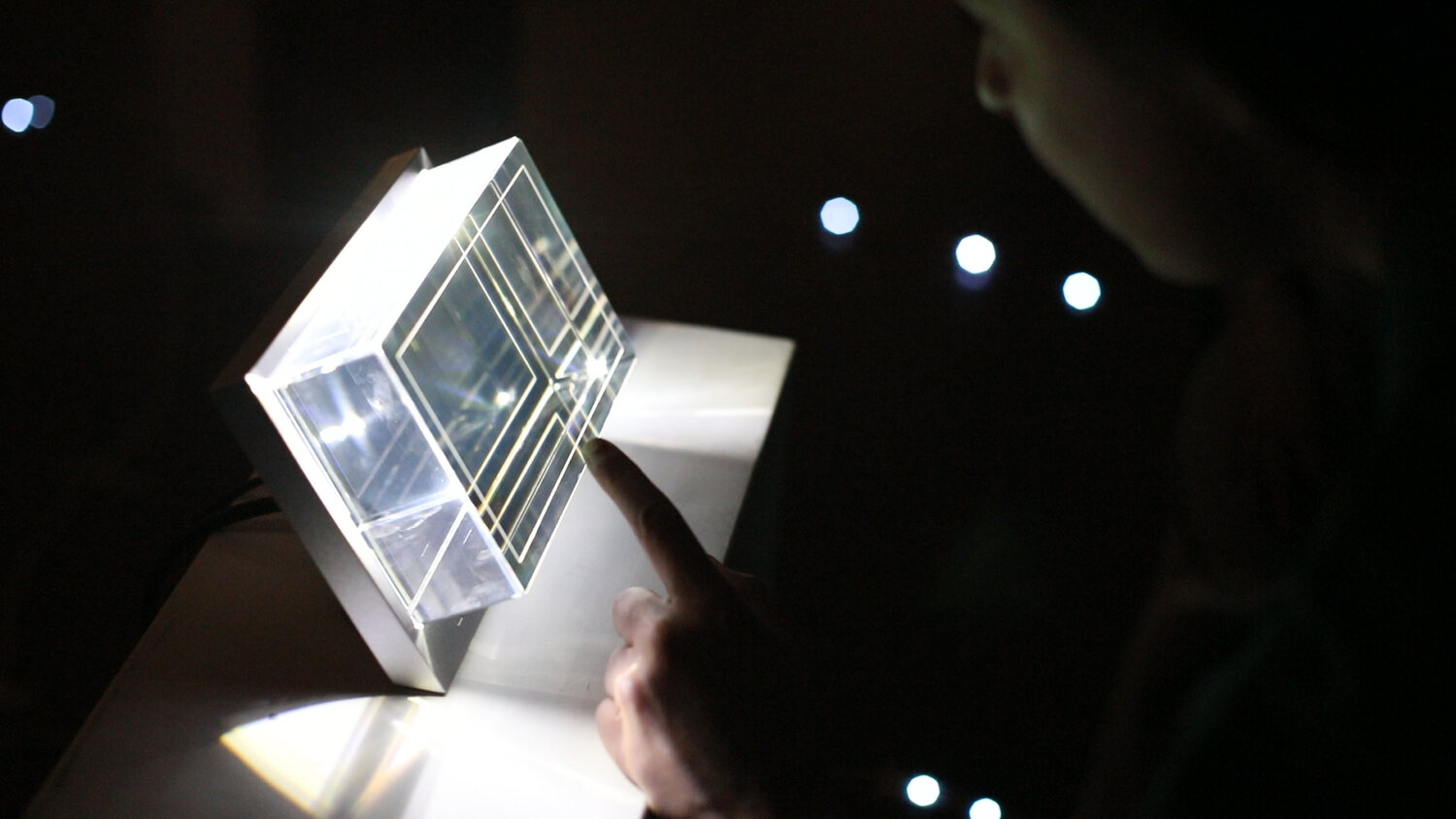 The central “hologram finale” prototype—a clear acrylic cube with etched concentric lines—emits light to form a low-fi planet model, visualizing the cumulative impact of each team’s energy choices.