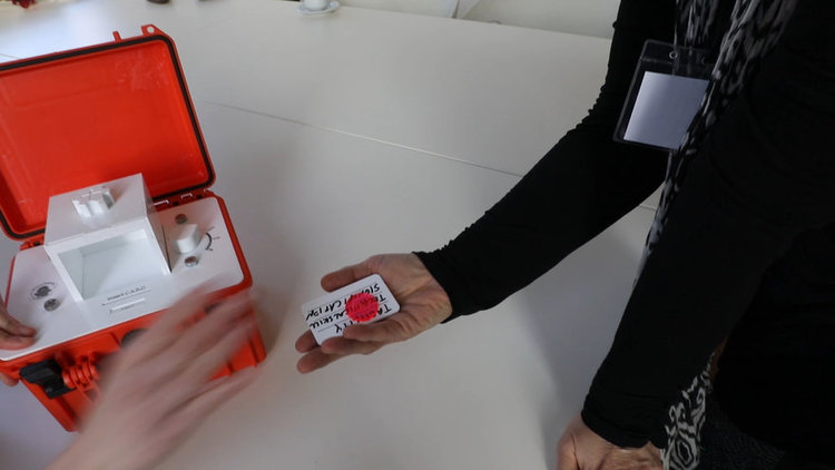 Participant holding a custom punchcard receipt printed with algorithmic output (“E pluribus pauca”), highlighting how deletion algorithms generate tangible artifacts for expert review and reflection.